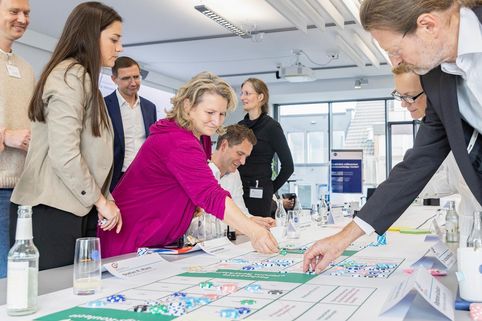 Mehrere Personen um einen Tisch mit Planspiel zur Kreislaufwirtschaft