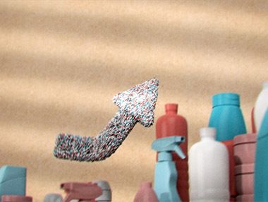 Pfeil aus Kunststoffpellets über Flaschen symbolisiert Wiederverwertung von Kunststoff-Verpackungen